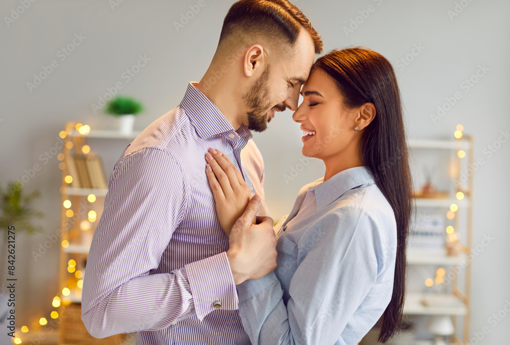 Naklejka premium Couple in love dancing at home. Profile, side view of a happy man and woman smiling, dancing and having fun together. Romance, love, affection, Valentine's Day, marriage anniversary concept