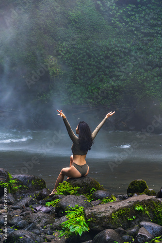 Woman in Grey Bodysuit Embracing Nature by Misty Waterfall