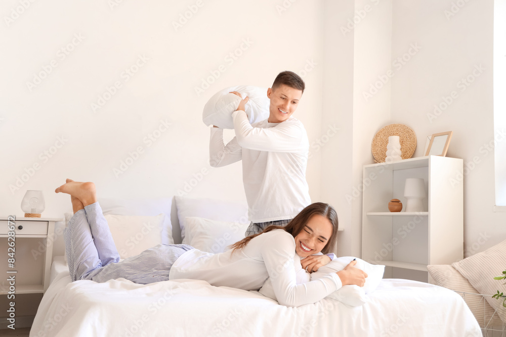 Young couple fighting pillows in bedroom Young couple fighting pillows in bedroom