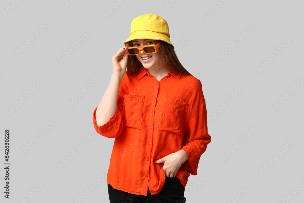 Stylish young girl wearing hat, sunglasses and shirt on light background Stylish young girl wearing hat, sunglasses and shirt on light background