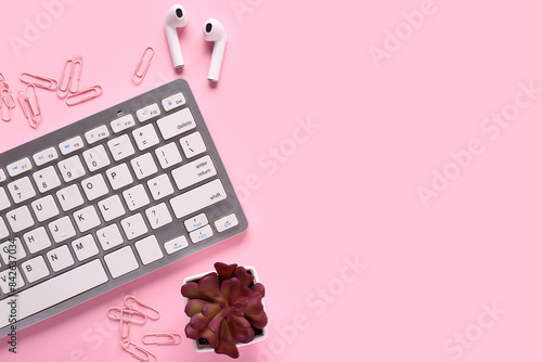 Grey computer keyboard, earphones and paper clips on pink background. Top view © Pixel-Shot