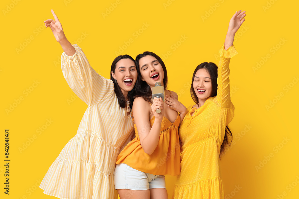 Beautiful young women with microphone on yellow background. Summer party