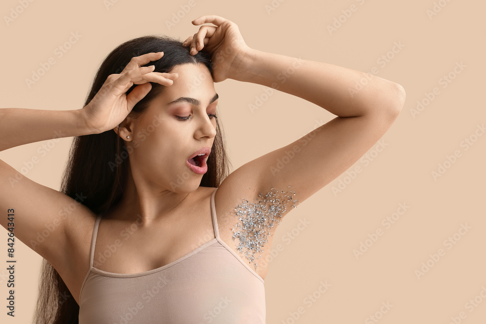 Beautiful young shocked woman with confetti on her armpit against beige background. Depilation concept Beautiful young shocked woman with confetti on her armpit against beige background. Depilation concept