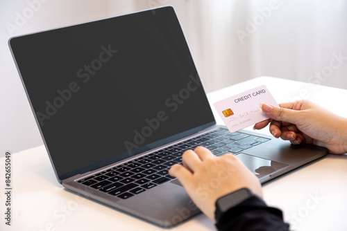 Consumer woman hand holding a mock up credit card, ready to spending pay online finance shopping according to discount products via laptop from home office