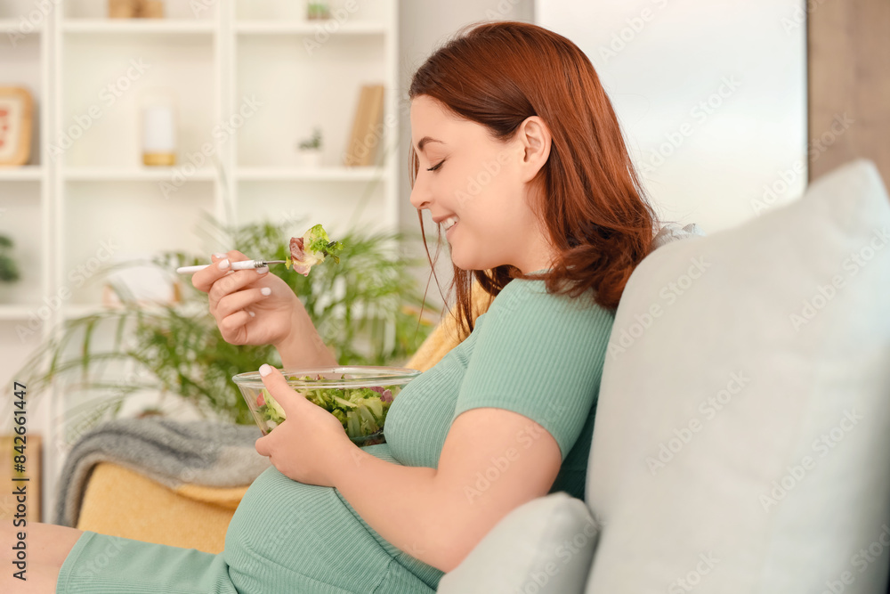 Young pregnant woman eating fresh vegetable salad sitting on sofa at home Young pregnant woman eating fresh vegetable salad sitting on sofa at home