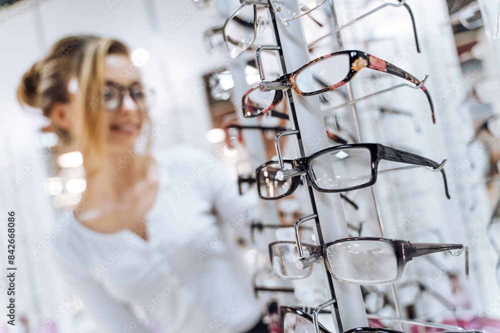 A woman is looking at a display of eyeglasses. She is smiling and she is happy A woman is looking at a display of eyeglasses. She is smiling and she is happy