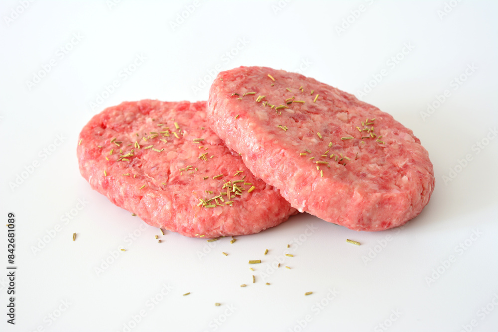 two hamburgers with seasoning on them isolated on white background two hamburgers with seasoning on them isolated on white background
