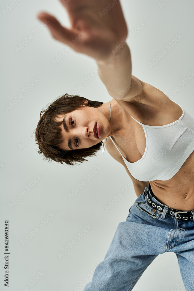 Stylish young woman posing gracefully in white tank top and jeans. Stylish young woman posing gracefully in white tank top and jeans.