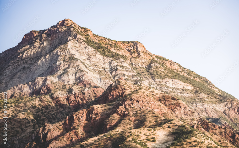 Texture of a rocky mountain range with rocky cliffs and vegetation in the morning at dawn in the mountains of Tajikistan