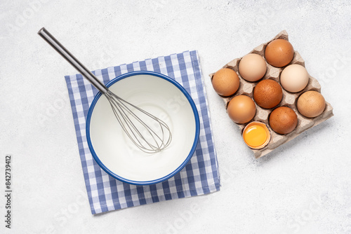 Eggs, bowl and whisk on white background with copy space. Baking background top view