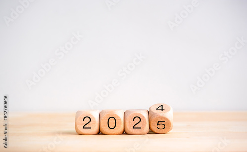 2025 happy new year with change to new era concept. Flipping the 2024 to 2025 year calendar numbers on wooden cube blocks isolated on wood table and white banner background, eco and minimal style.. photo