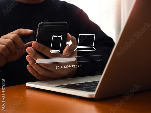 File transfer, data migration, transmission, backup files concept. Loading progress bar and smartphone sending to computer icons appear while person using mobile phone to sharing file with 2 devices. photo