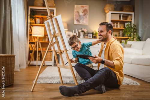 Father teach mentor son to create art at home on easel with brush