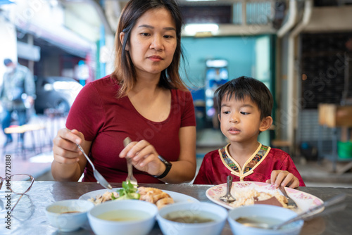 Little asian boy with mom eat steam rice in street food local city Yaowarat