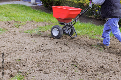 Foto Drop lawn spreader used for sowing lawn grass seeds in residential back yard