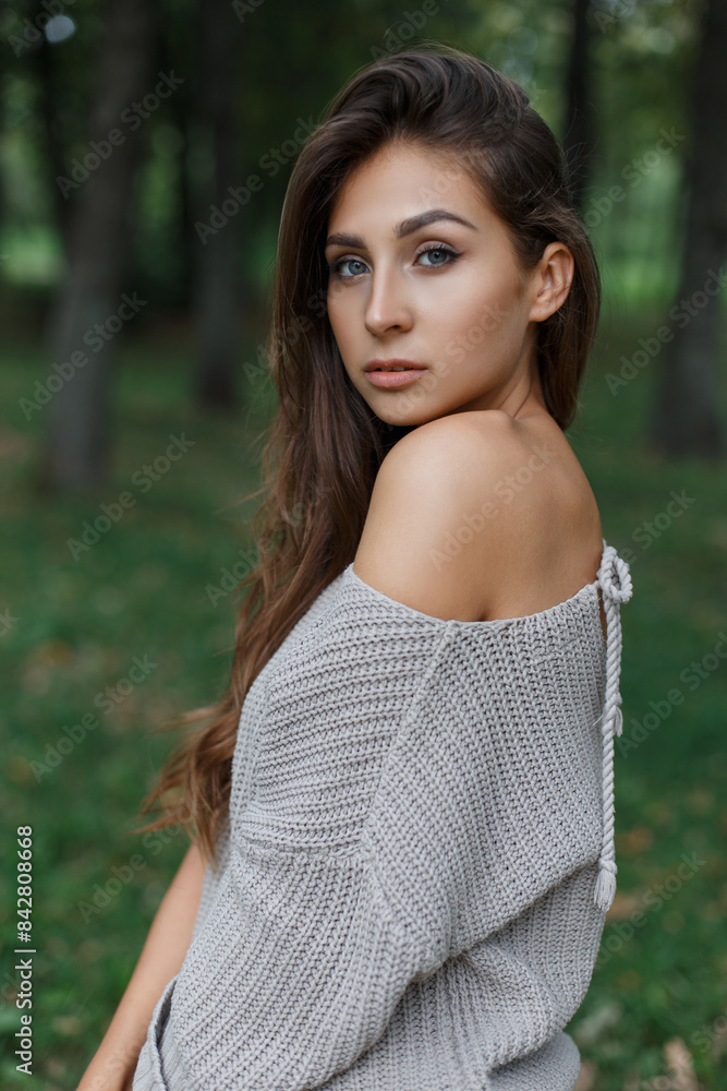 Beautiful young fresh woman with clean skin in a fashion knitted sweater walking in the park on a green background Beautiful young fresh woman with clean skin in a fashion knitted sweater walking in the park on a green background