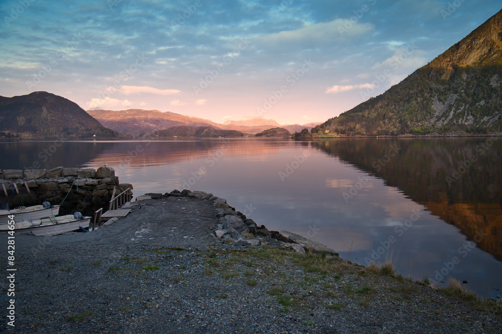 Fototapeta premium Norwegian landscape. View over a small harbor to the fjord at sunset behind the mountain