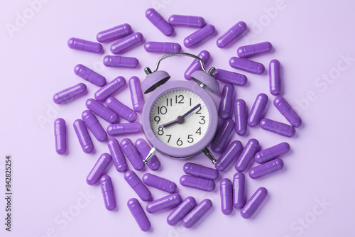 Quadro su tela Sleeping pill concept with capsules and alarm clock on purple background