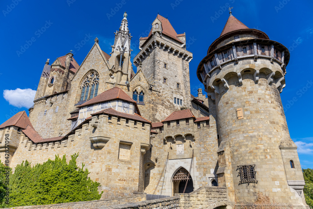 Castle landmark under blue sky. Medieval castle in Austria. Ancient historical sights around Vienna. Castle Kreuzenstein old building from outside Castle landmark under blue sky. Medieval castle in Austria. Ancient historical sights around Vienna. Castle Kreuzenstein old building from outside