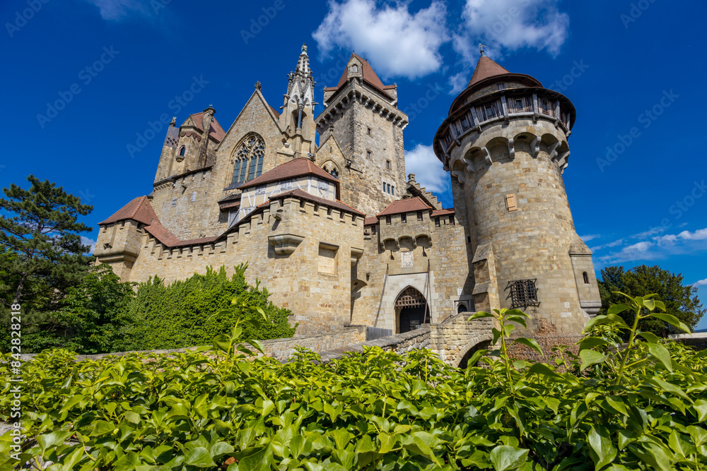 Castle landmark under blue sky. Medieval castle in Austria. Ancient historical sights around Vienna. Castle Kreuzenstein old building from outside Castle landmark under blue sky. Medieval castle in Austria. Ancient historical sights around Vienna. Castle Kreuzenstein old building from outside