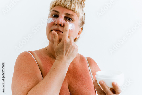 Foto Middle-aged woman applying after-sun cream