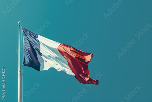 A detailed shot of the French flag fluttering in the wind on a solid blue background