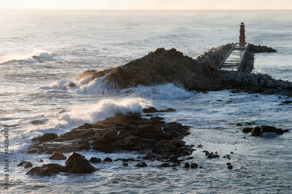 Naklejka premium View of the surf on the rocky seaside after sunrise