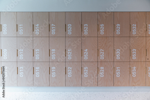 A row of modern, wooden lockers with white numbers, set in a clean, well-lit, and minimalist environment. 