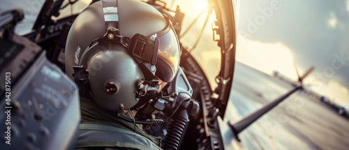 A pilot in a cockpit at sunset, the light reflecting off his helmet, evoking a sense of adventure and focus as he prepares for takeoff. photo