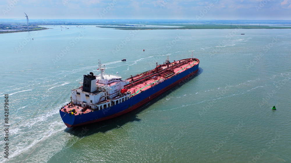 Aerial shot of oil tanker approaching port with tugboats in UK Aerial shot of oil tanker approaching port with tugboats in UK