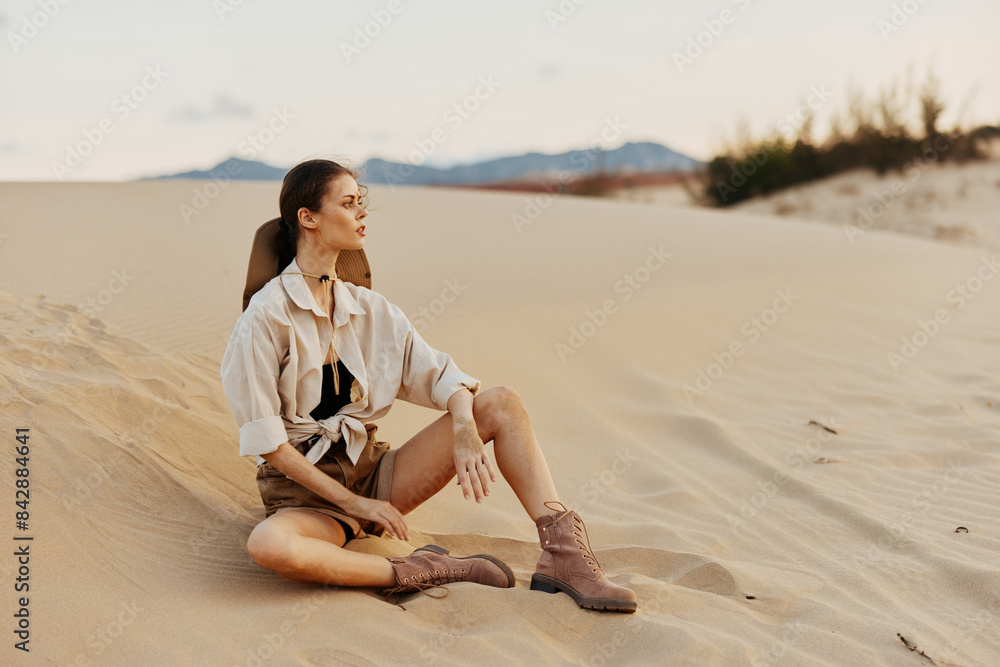 Lonely woman sitting on sand dune in the middle of desert under clear blue sky Lonely woman sitting on sand dune in the middle of desert under clear blue sky