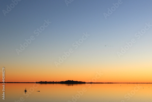 Seen from the banks of the Arnel pond, birds fly in a triangle above the Maguelone Cathedral (Villeneuve les Maguelone, France)

