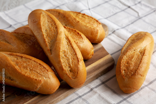 Homemade Mini baguettes on a wooden board, side view. photo