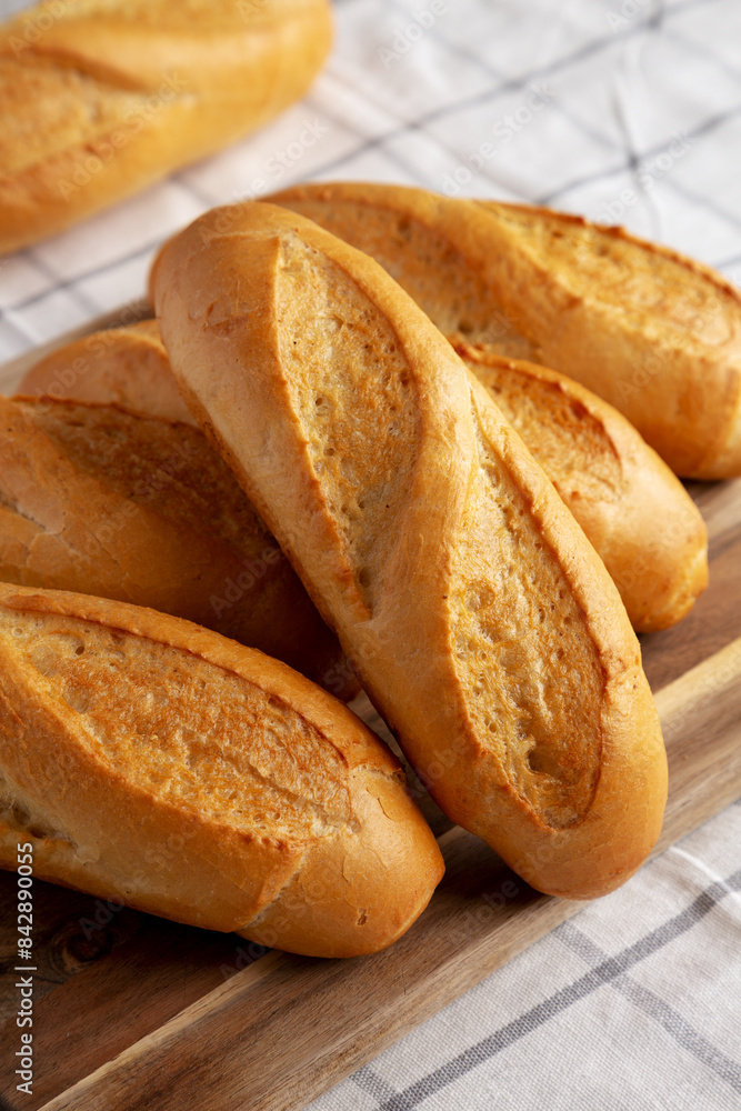 Homemade Mini baguettes on a wooden board, side view. Close-up. Homemade Mini baguettes on a wooden board, side view. Close-up.