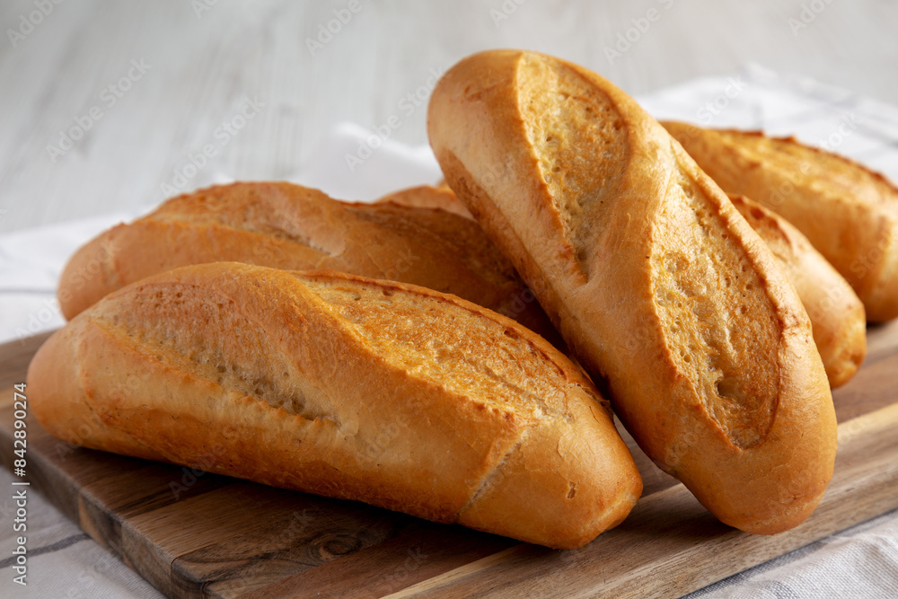 Homemade Mini baguettes on a wooden board, side view. Close-up. Homemade Mini baguettes on a wooden board, side view. Close-up.