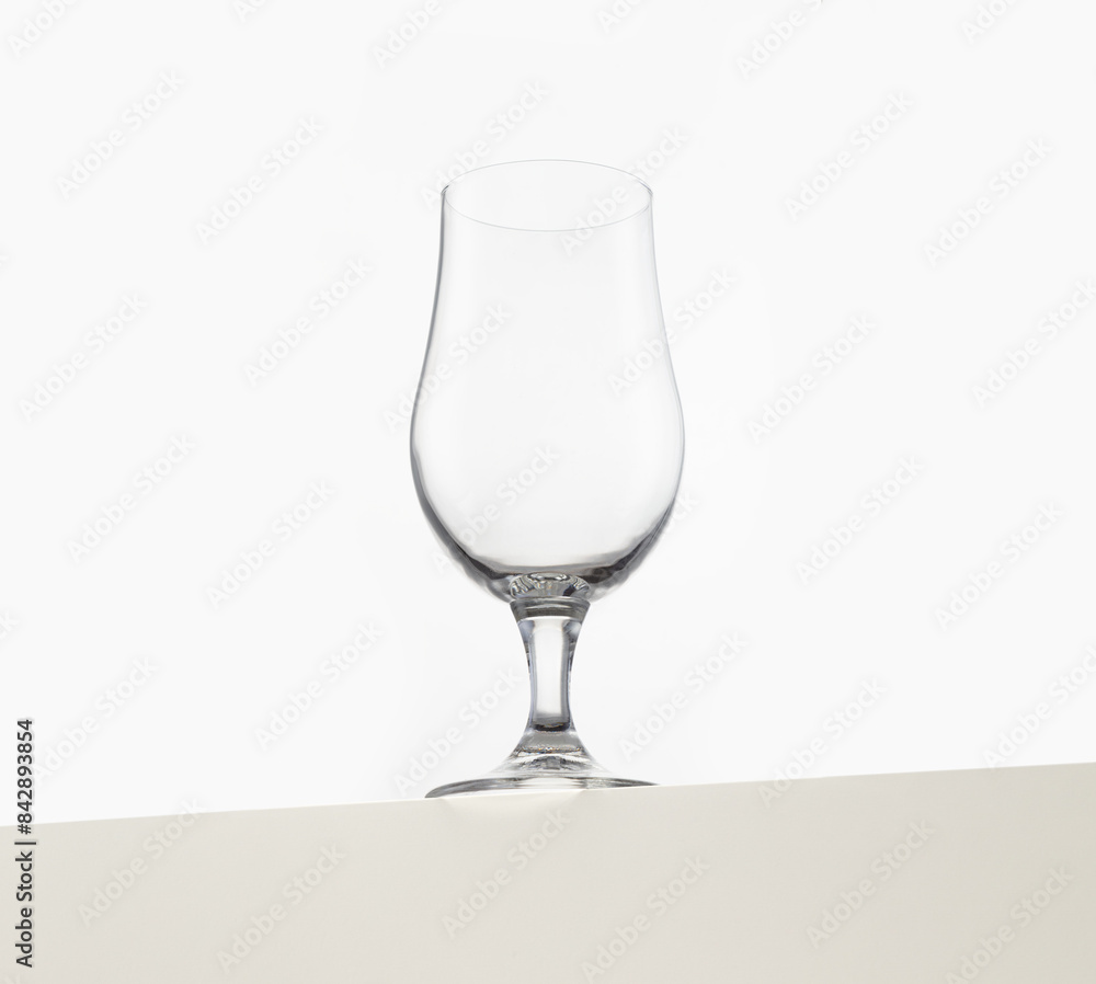A clear, empty wine glass is elegantly displayed against a plain white background. The glassware's sleek and simple design emphasizes its clean lines and transparency A clear, empty wine glass is elegantly displayed against a plain white background. The glassware's sleek and simple design emphasizes its clean lines and transparency