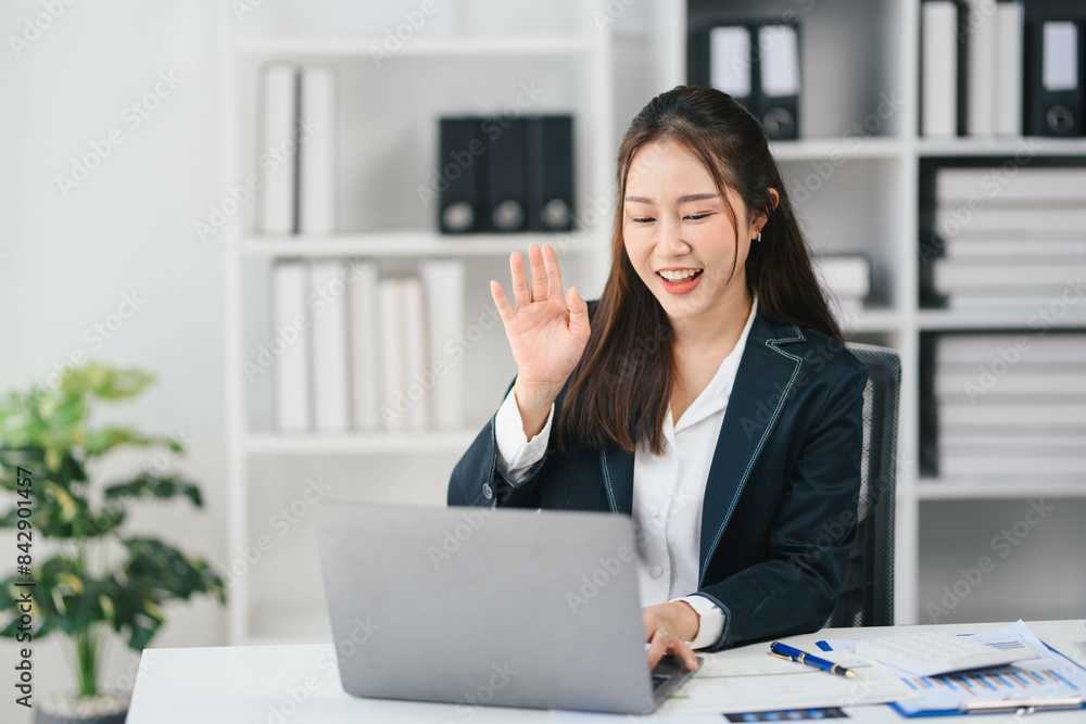 Business woman is sitting at a desk with a laptop and smiling Business woman is sitting at a desk with a laptop and smiling