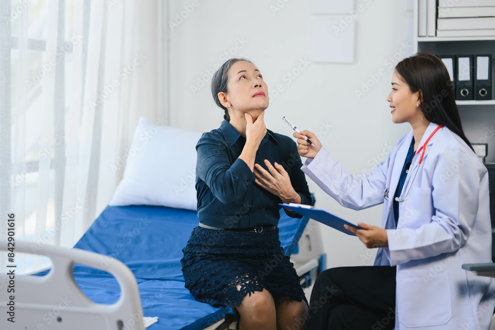 Obraz premium Older woman is sitting on a hospital bed while a doctor examines her
