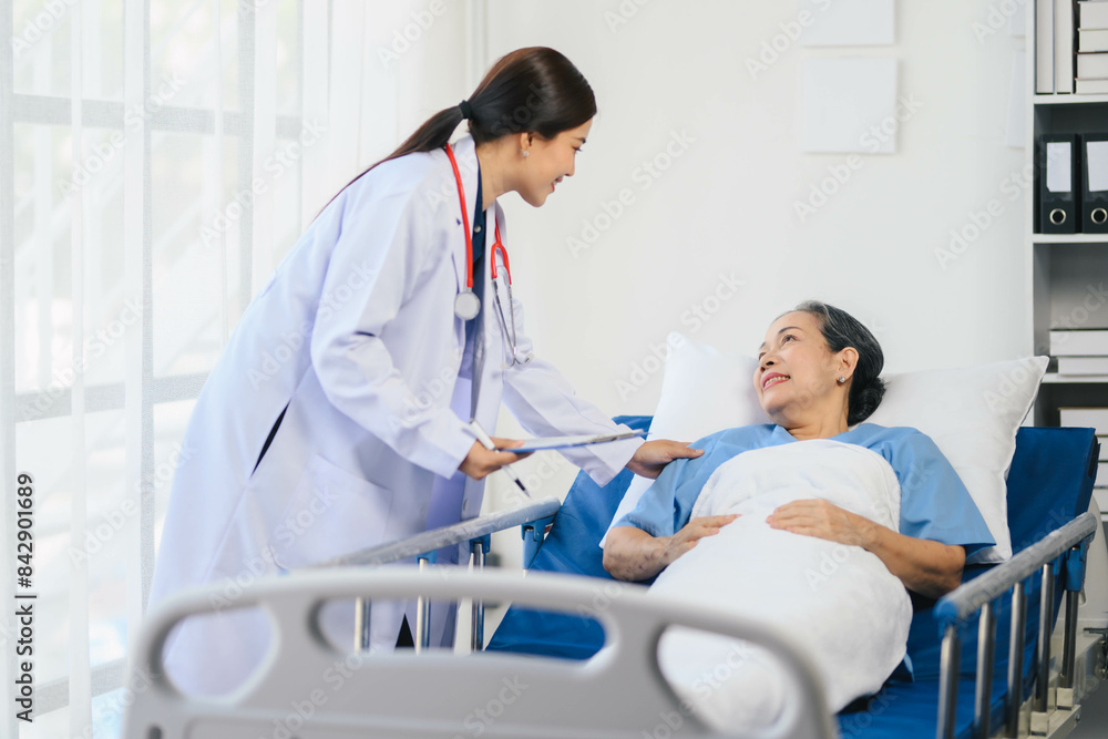 Obraz premium Doctor woman in a white coat is talking to an older woman in a hospital bed