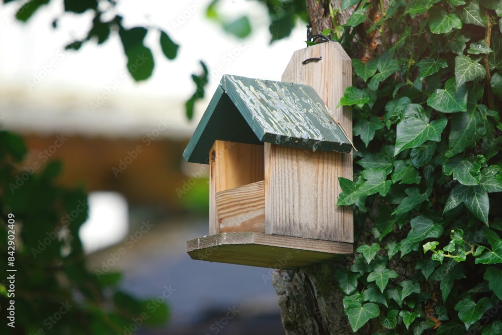 Homemade bird nesting box hangs on a tree. Horizontal image with selective focus. Homemade bird nesting box hangs on a tree. Horizontal image with selective focus.