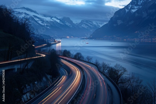 Scenic dusk drive through majestic mountain range with sparkling lake and glowing car lights