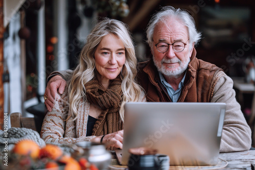 White grandfather sitting on table looking laptop, communicate online © Aris