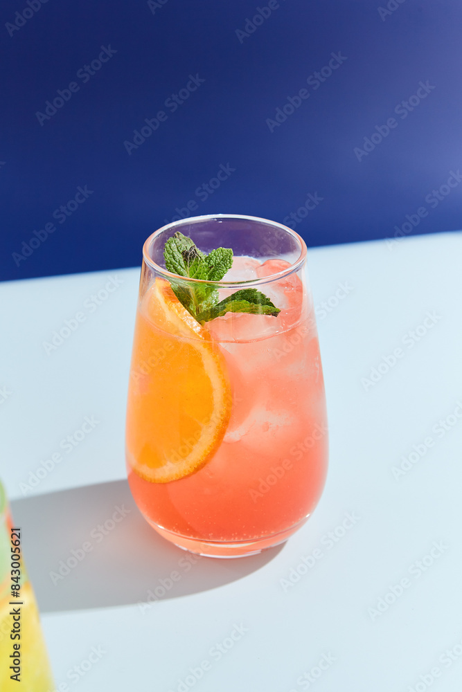 Refreshing Peach and Orange Lemonade in a Highball Glass Against a Blue Background Refreshing Peach and Orange Lemonade in a Highball Glass Against a Blue Background