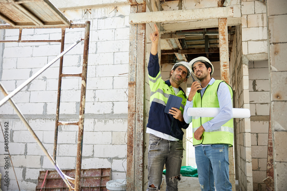 workers or architects working on tablet and pointing up to something at construction site workers or architects working on tablet and pointing up to something at construction site