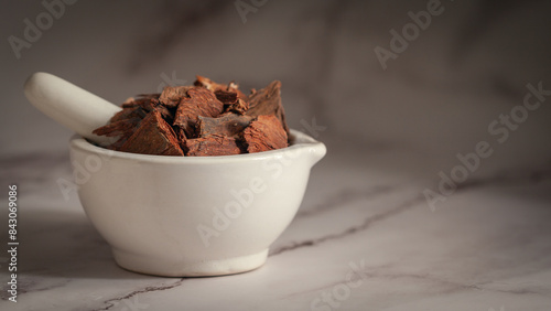 Close-up of Dry Organic Arjuna (Terminalia Arjuna) Barks, in white ceramic mortar and pestle, on a marble background. photo