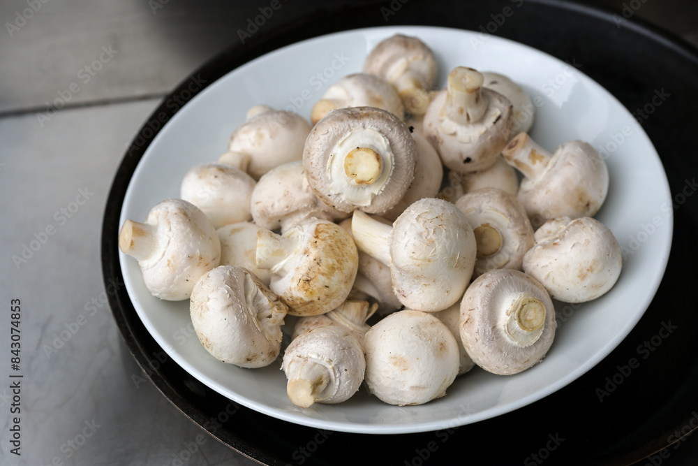 Fresh raw champignon mushrooms in a white and black bowl for a healthy vegetarian dish Fresh raw champignon mushrooms in a white and black bowl for a healthy vegetarian dish