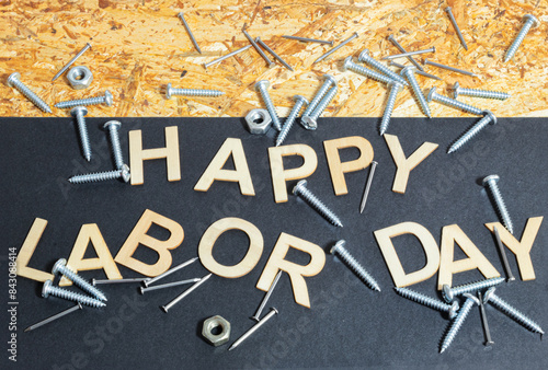Happy Labor Day sign among nails, screws and nuts. Wood background.
