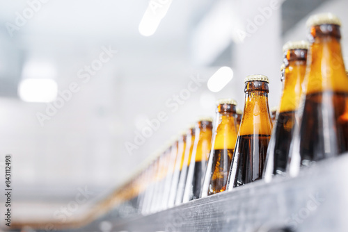 Automated modern beer bottling factory line with rows of filled bottles