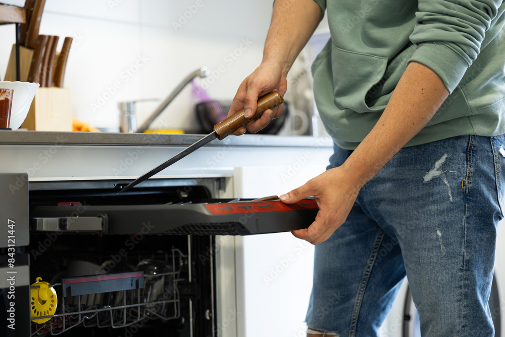 young man putting a dishwasher in his house after a meal. Man doing housework. young man putting a dishwasher in his house after a meal. Man doing housework.