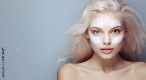 Beautiful young Caucasian blonde woman with facial mask on her face on a background with Copy Space. Blonde woman with clay mask on her face. Blonde female with cosmetic Facial Mask. copy space.